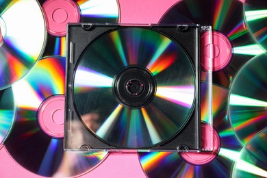 Photo of Many shiny compact discs on pink background, flat lay