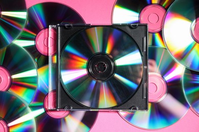 Photo of Many shiny compact discs on pink background, flat lay