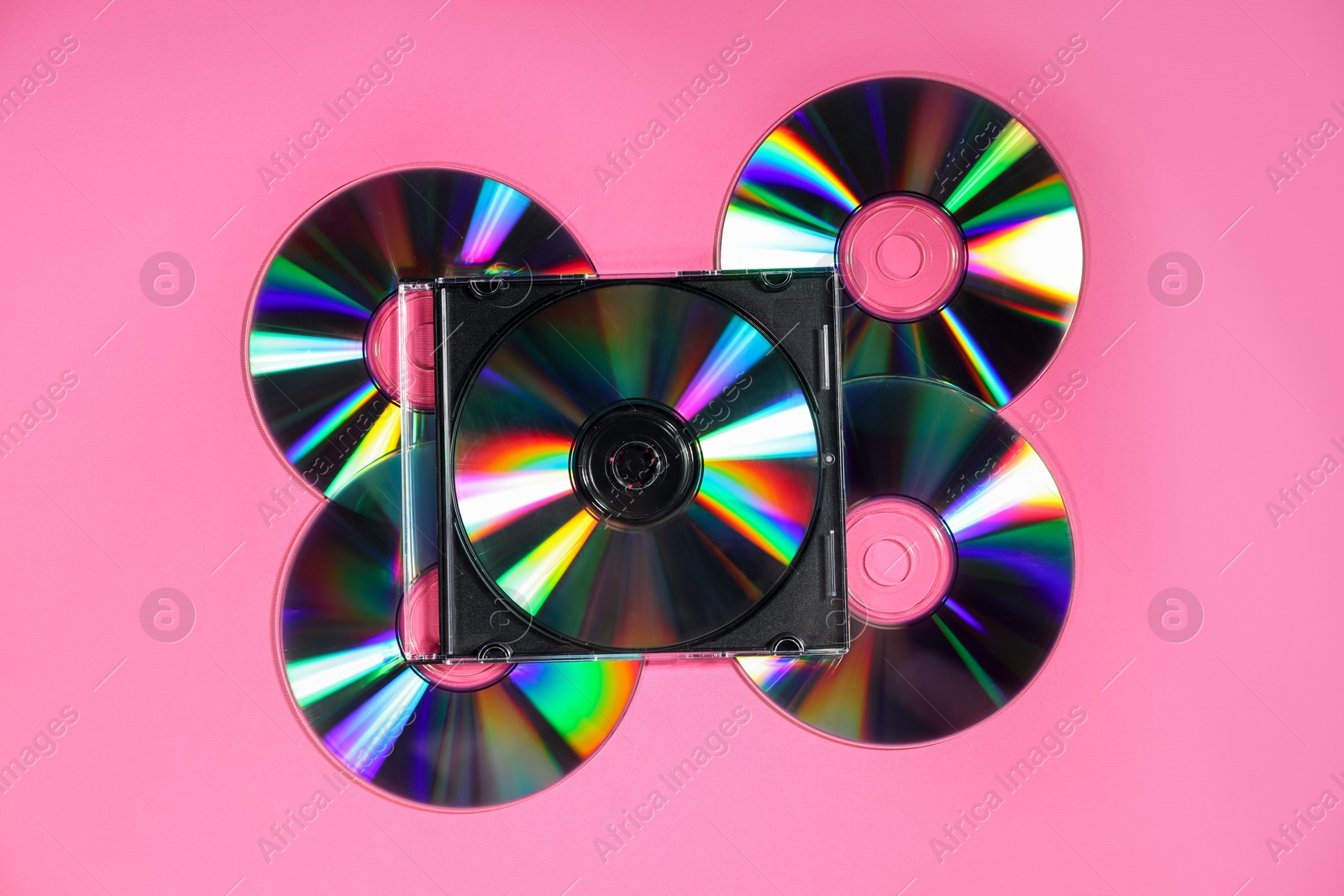 Photo of Many shiny compact discs on pink background, flat lay