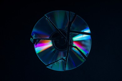 Photo of Broken compact disc on black background, top view