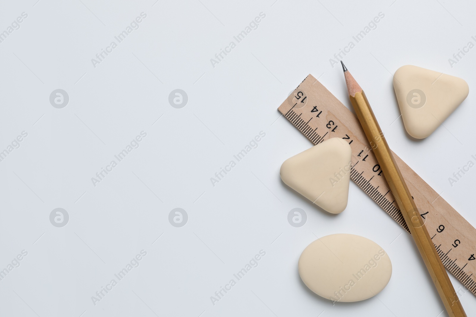 Photo of Erasers, ruler and pencil on white background, flat lay. Space for text