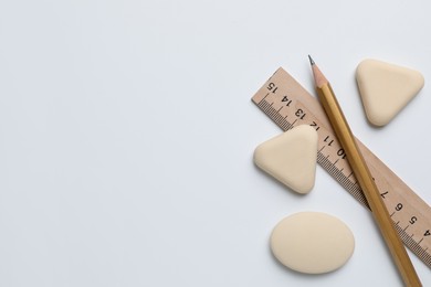 Photo of Erasers, ruler and pencil on white background, flat lay. Space for text