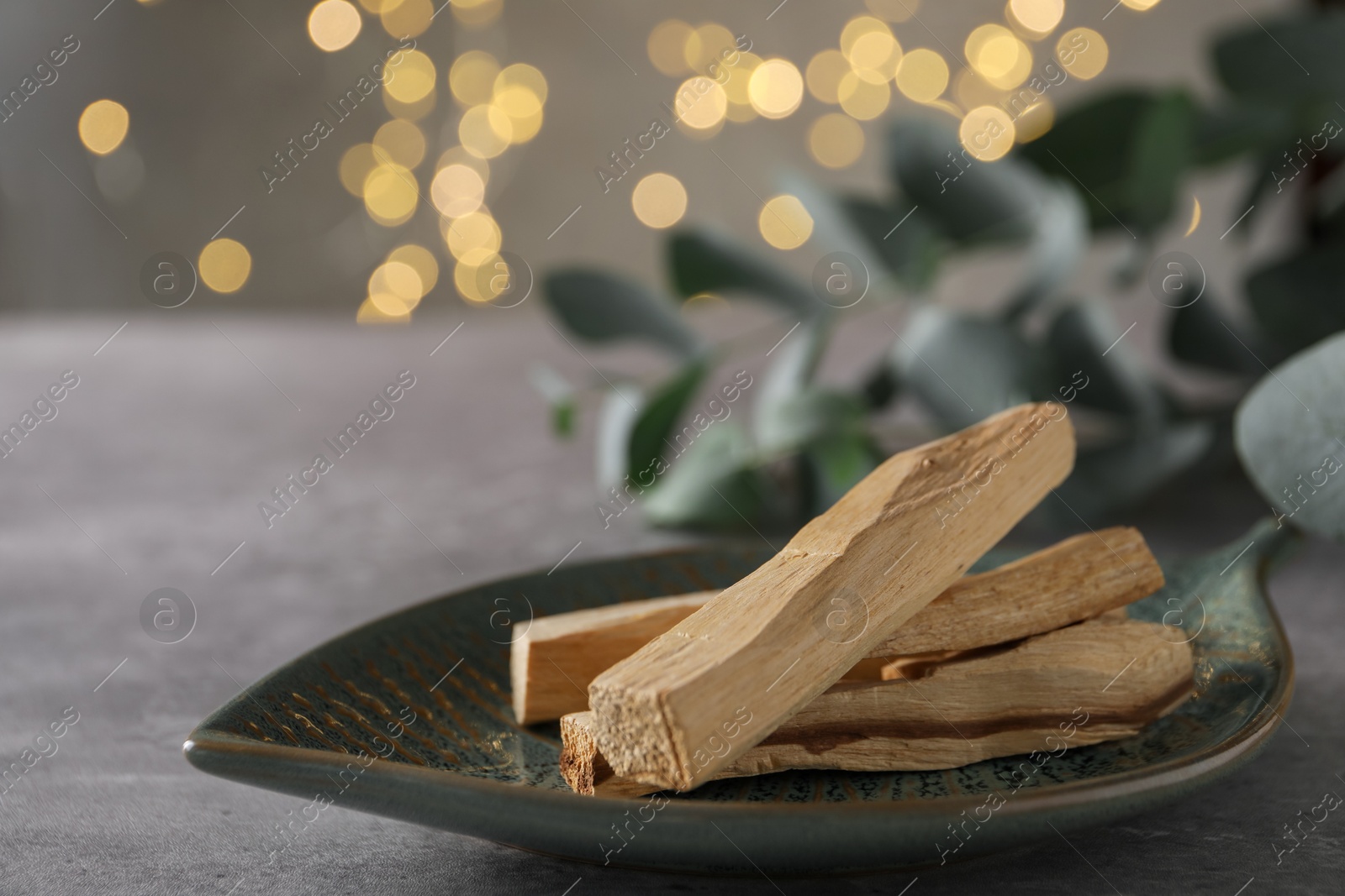 Photo of Palo santo sticks and eucalyptus leaves on grey table, closeup