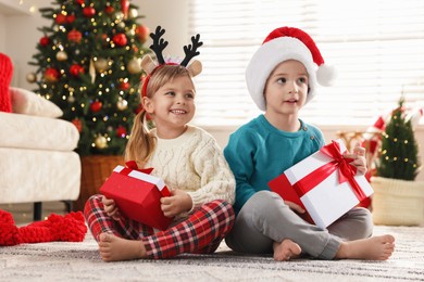 Photo of Happy children with Christmas gifts on floor at home