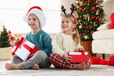 Photo of Happy children with Christmas gifts on floor at home