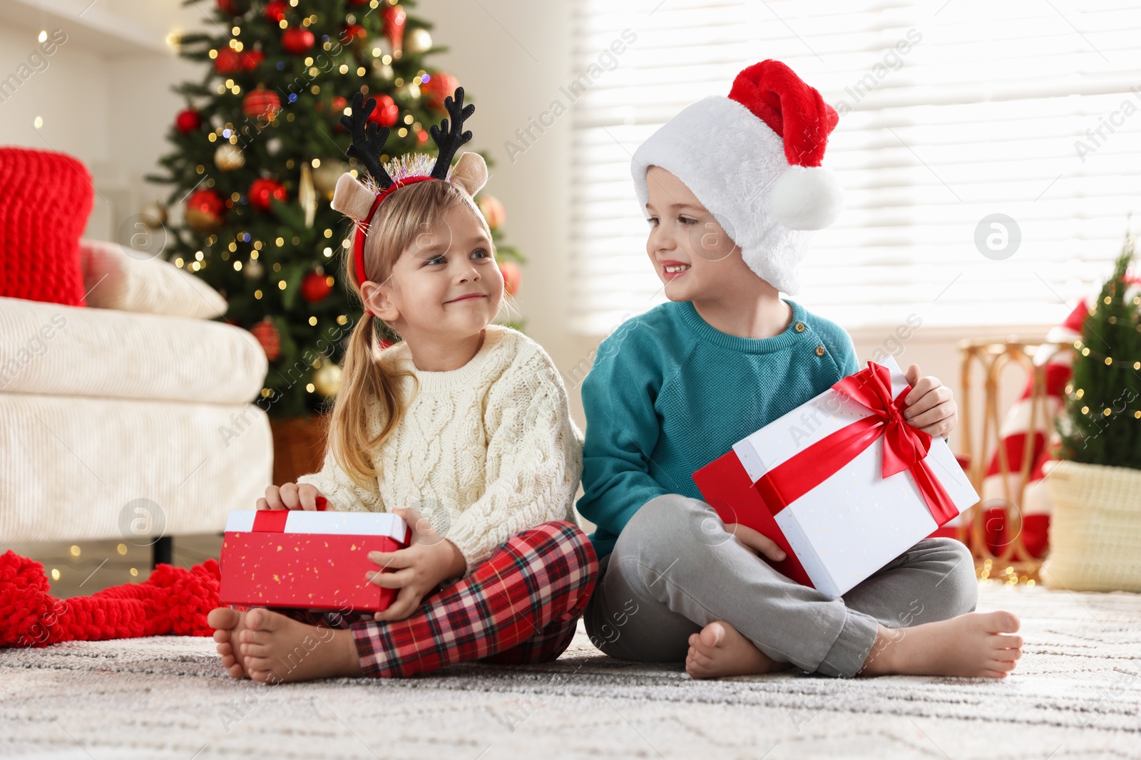 Photo of Happy children with Christmas gifts on floor at home