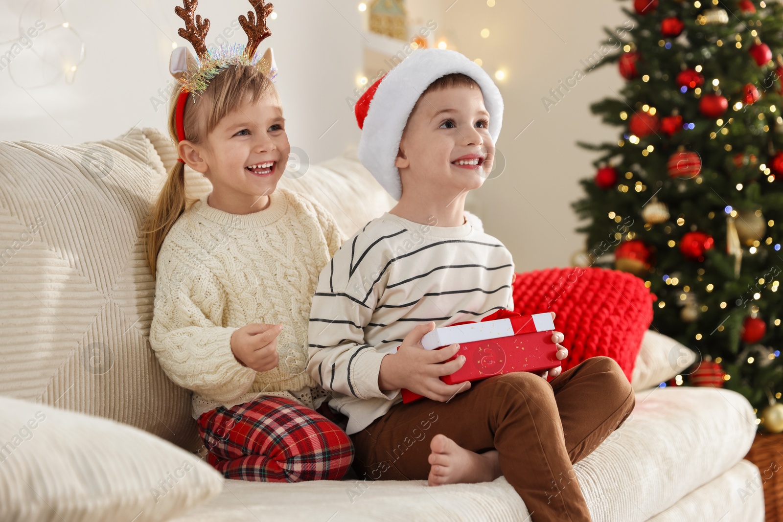 Photo of Happy children with Christmas gift on sofa at home