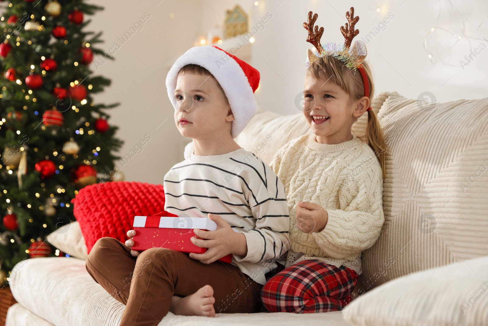 Photo of Happy children with Christmas gift on sofa at home