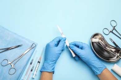 Photo of Doctor with different surgical tools on light blue background, top view