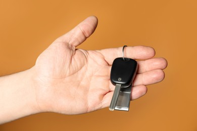 Photo of Man with car key and keychain on orange background, closeup