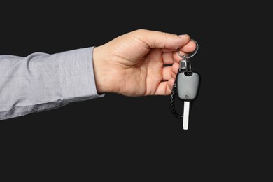 Photo of Woman with car key and keychain on black background, closeup