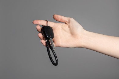 Photo of Woman with car key and keychain on grey background, closeup