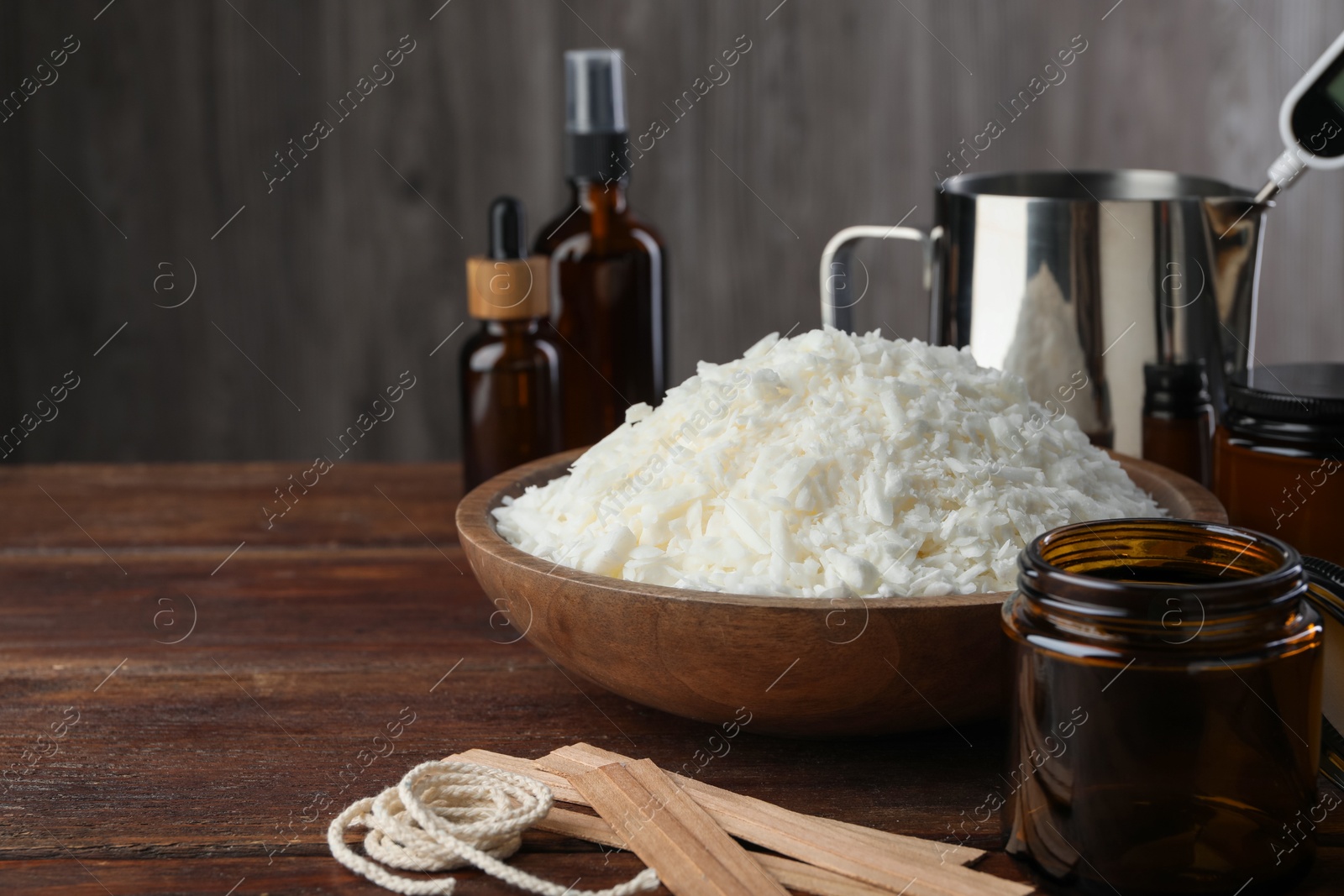 Photo of Soy wax and other supplies for making candles on wooden table, closeup