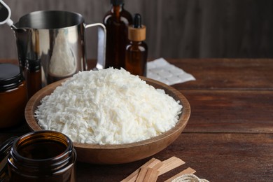 Photo of Soy wax and other supplies for making candles on wooden table, closeup