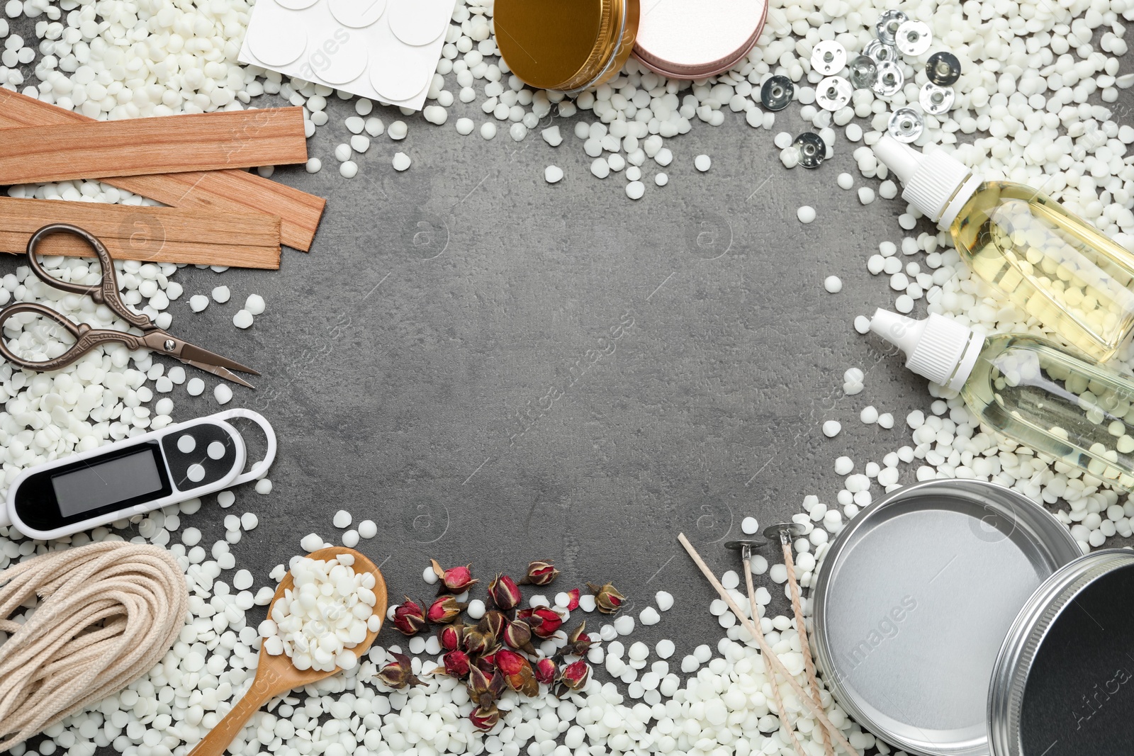 Photo of Frame of soy wax and other supplies for making candles on grey table, flat lay. Space for text