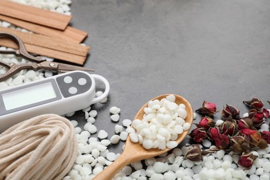 Photo of Soy wax and other supplies for making candles on grey table, closeup. Space for text