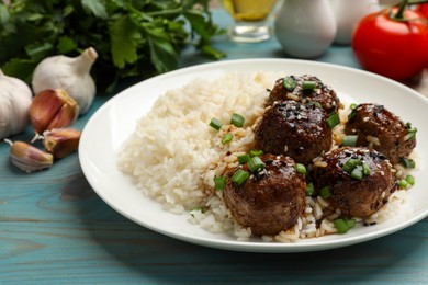 Photo of Delicious rice with meatballs, sauce and green onions on blue wooden table, closeup