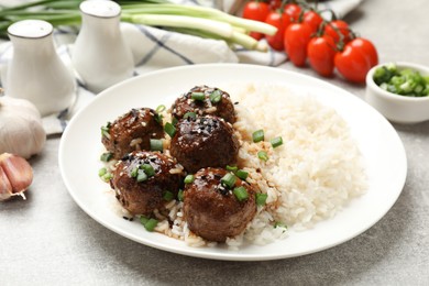 Photo of Delicious rice with meatballs, sauce and green onions on grey table, closeup