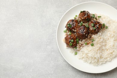 Photo of Delicious rice with meatballs, sauce and green onions on grey table, top view. Space for text