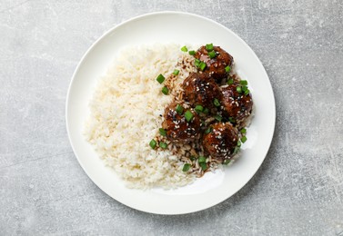 Photo of Delicious rice with meatballs, sauce and green onions on grey table, top view