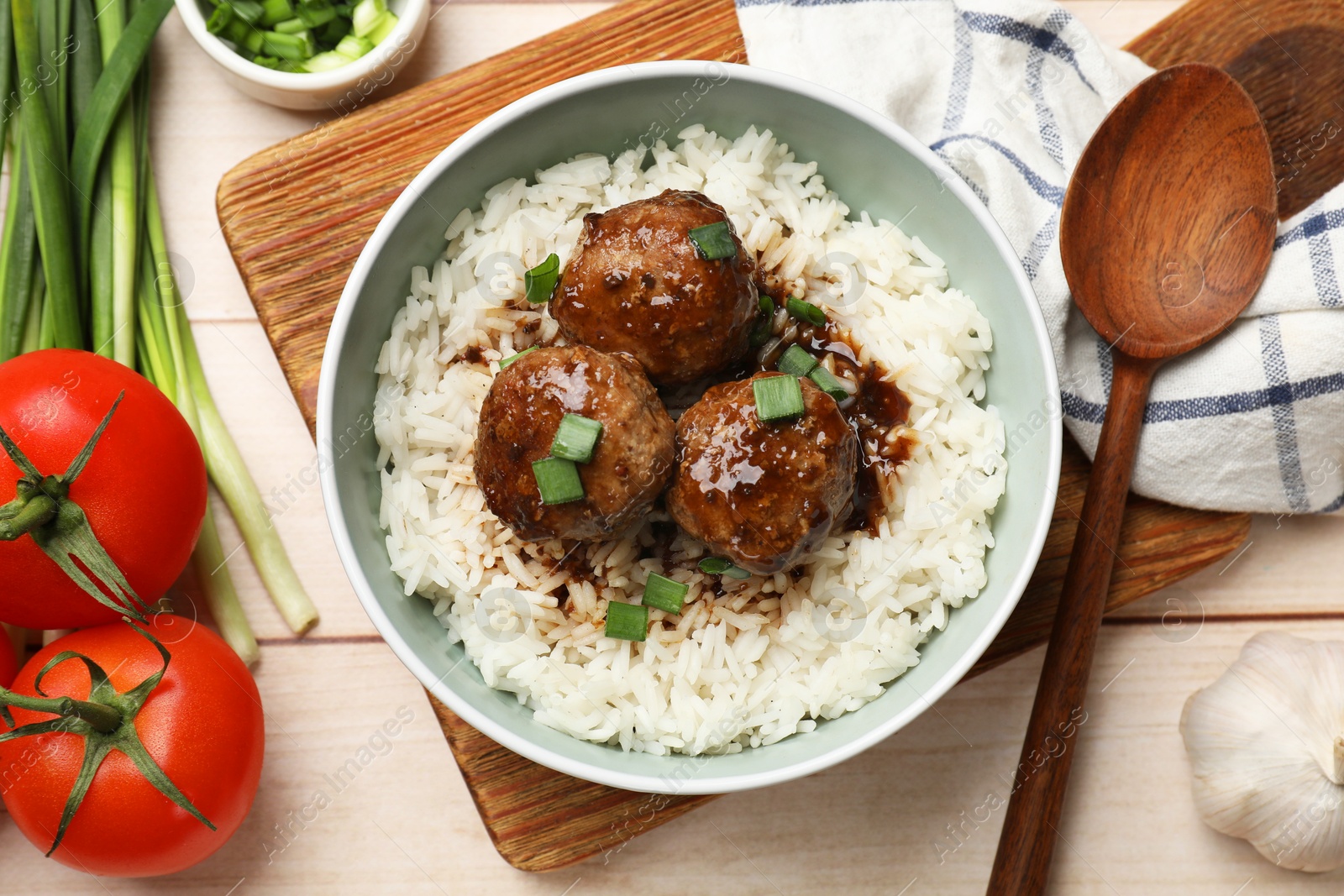 Photo of Delicious rice with meatballs, sauce and green onions on white wooden table, flat lay