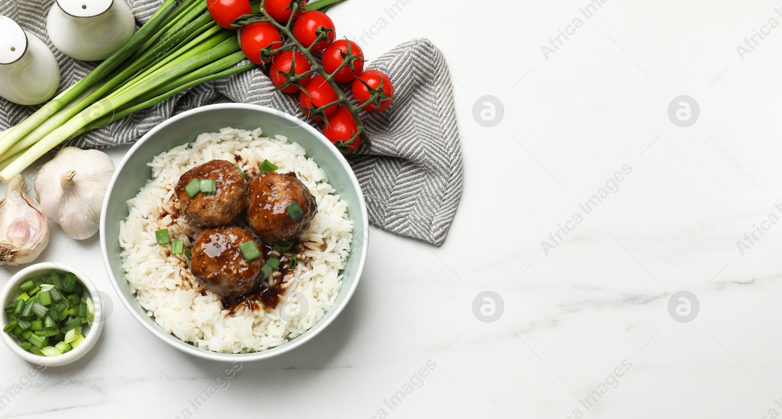 Photo of Delicious rice with meatballs, sauce and green onions on white marble table, flat lay. Space for text