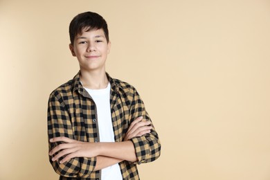 Photo of Portrait of teenage boy with crossed arms on beige background, space for text