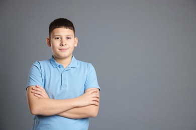 Photo of Portrait of teenage boy with crossed arms on grey background, space for text