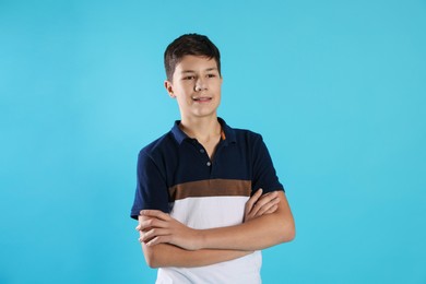 Photo of Portrait of teenage boy with crossed arms on light blue background