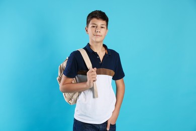 Photo of Portrait of teenage boy with backpack on light blue background