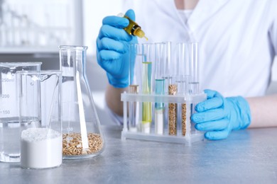 Photo of Laboratory testing. Scientist dripping liquid into test tube at table indoors, focus on glassware with sample