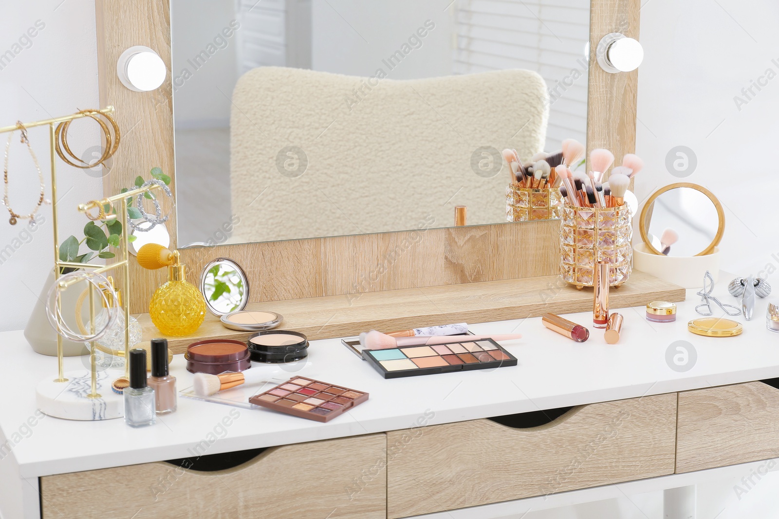 Photo of Makeup room. Dressing table with mirror, different beauty products and jewelry indoors