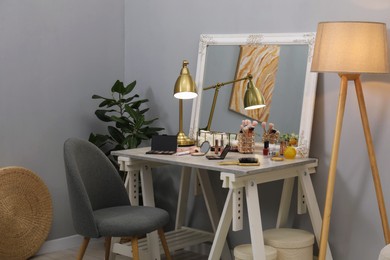 Photo of Makeup room. Mirror, dressing table, different beauty products and chair indoors