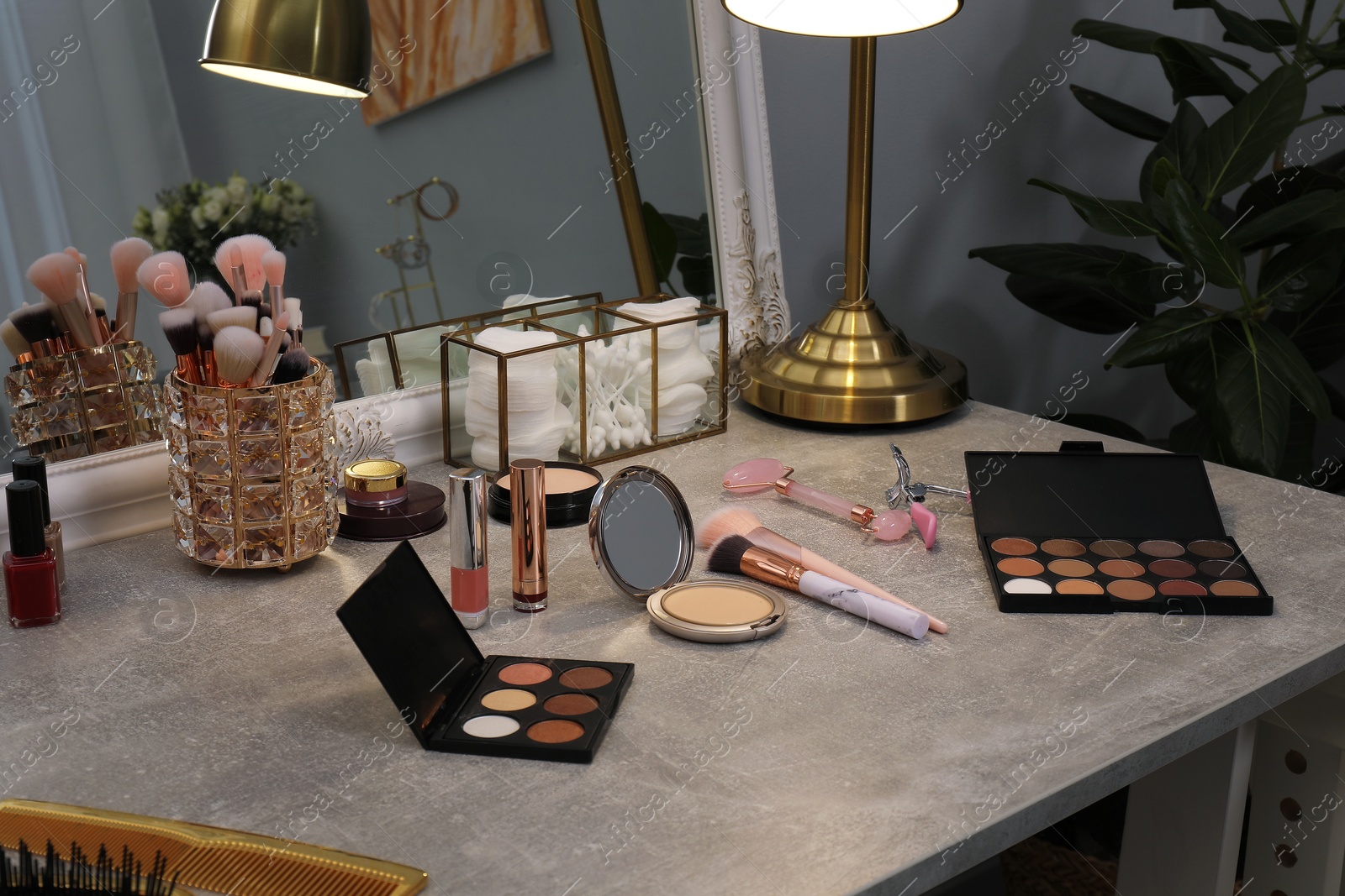 Photo of Makeup room. Different beauty products on grey dressing table and mirror indoors