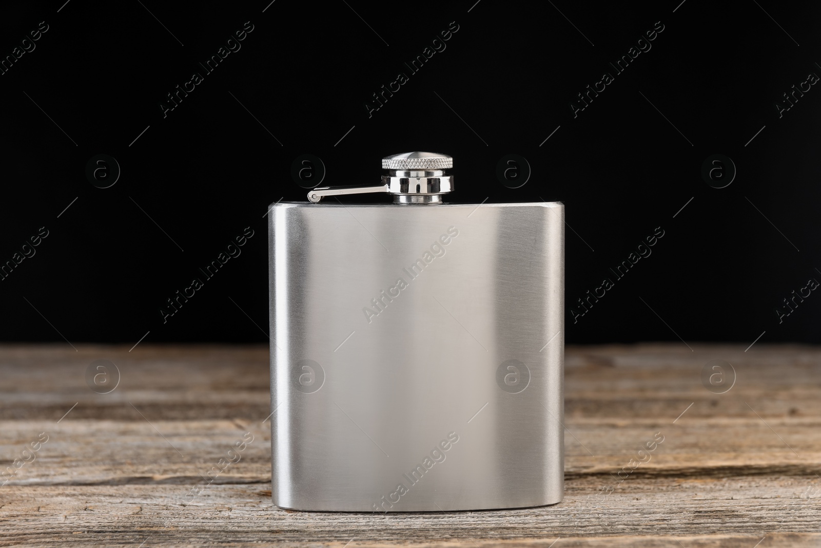 Photo of One hip flask on wooden table against black background