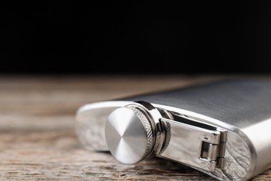 Photo of One hip flask on wooden table, closeup. Space for text