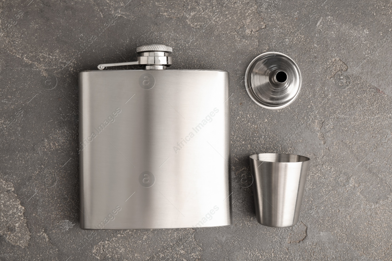 Photo of Hip flask, cup and funnel on grey table, flat lay