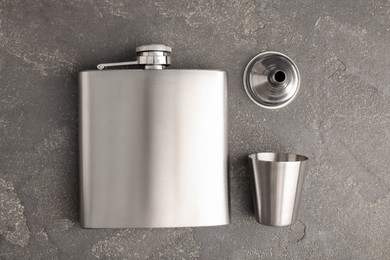 Photo of Hip flask, cup and funnel on grey table, flat lay