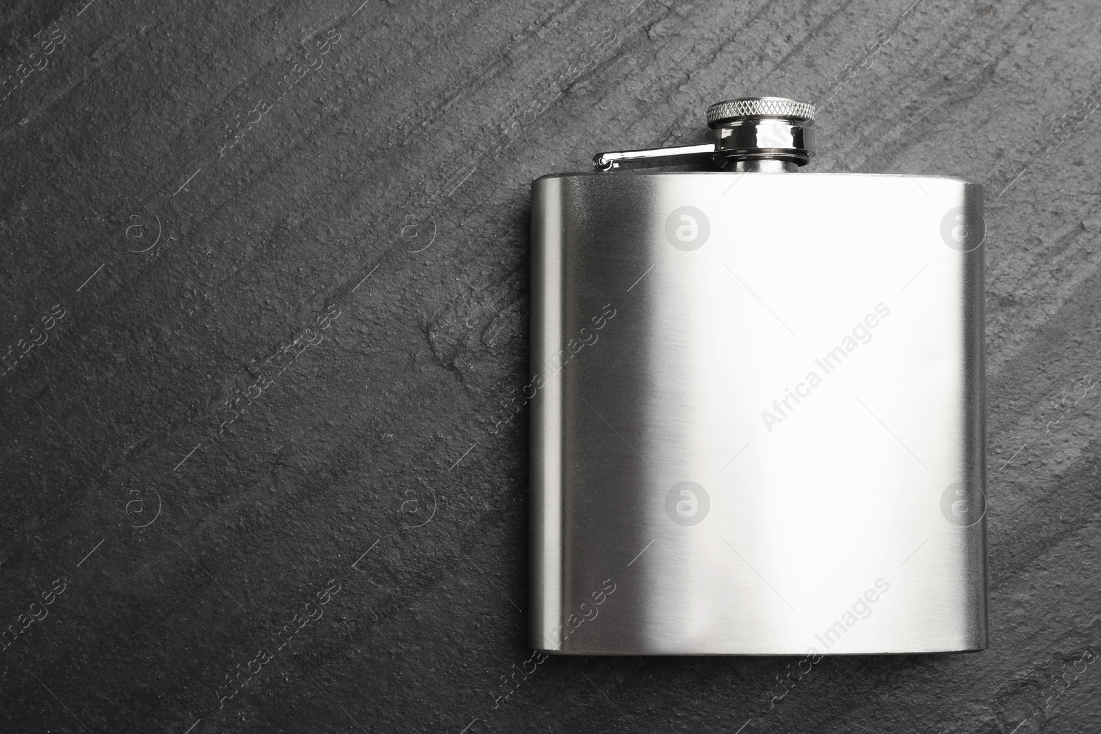 Photo of One hip flask on black table, top view. Space for text