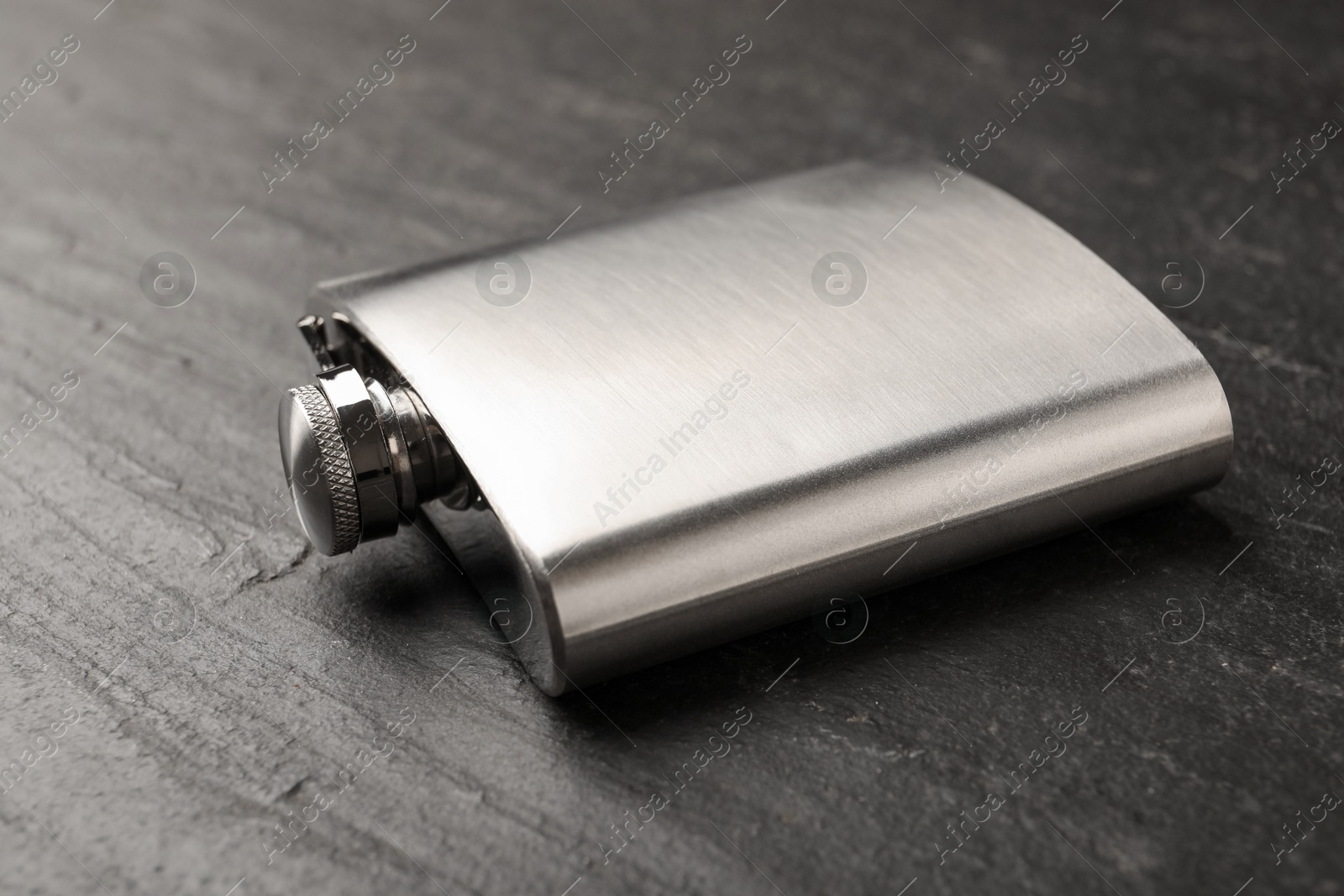 Photo of One hip flask on black table, closeup