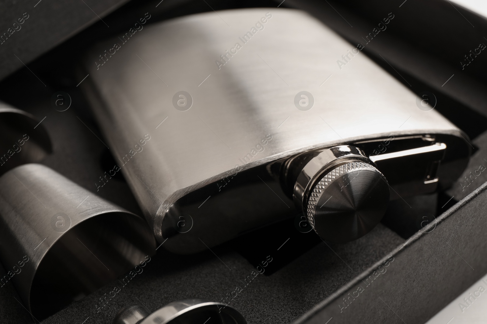 Photo of Hip flask, cups and funnel in package on table, closeup