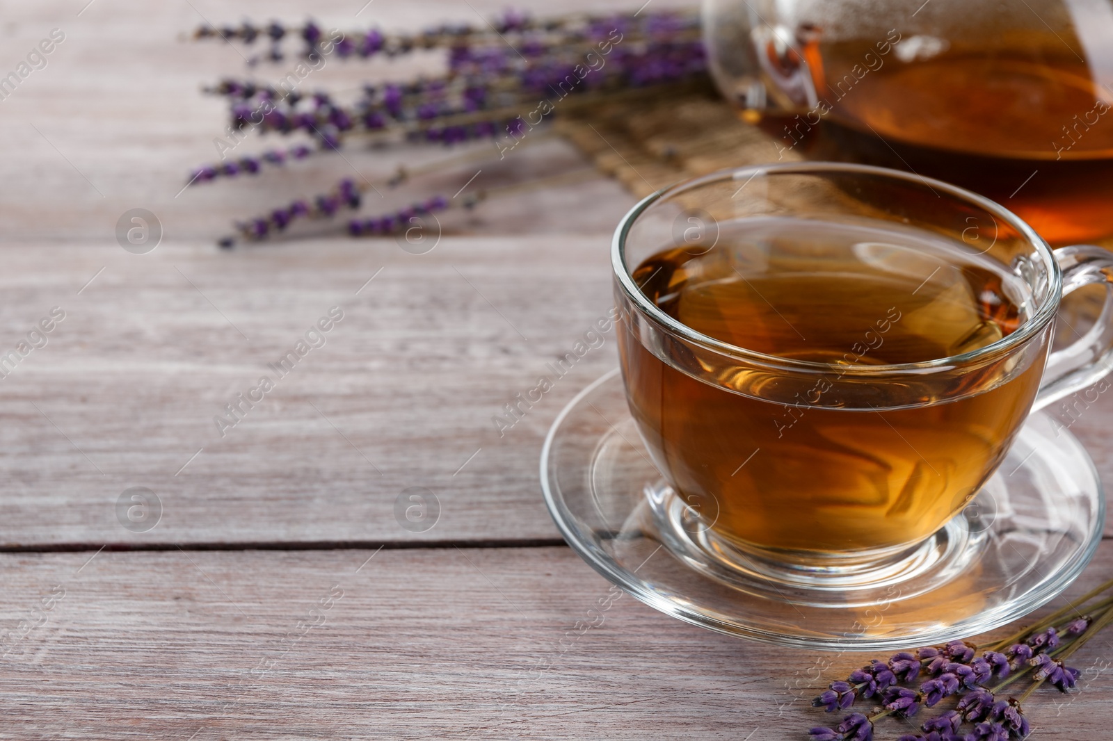 Aromatic lavender tea in glass cup and dry flowers on wooden table, closeup. Space for text Photo of Aromatic lavender tea in glass cup and dry flowers on wooden table, closeup. Space for text