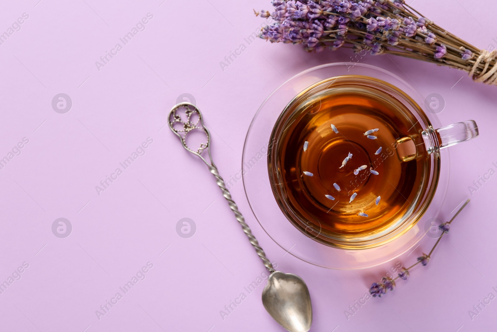 Aromatic lavender tea in glass cup, spoon and dry flowers on pink background, top view. Space for text Photo of Aromatic lavender tea in glass cup, spoon and dry flowers on pink background, top view. Space for text