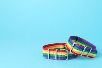 Photo of Two wristbands in LGBT colors on light blue background, space for text