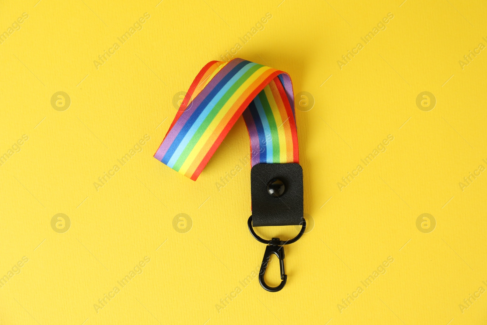 Photo of One keychain in LGBT colors on yellow background, top view