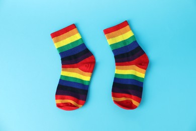 Photo of Pair of socks in LGBT colors on light blue background, flat lay