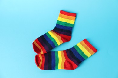 Photo of Pair of socks in LGBT colors on light blue background, flat lay