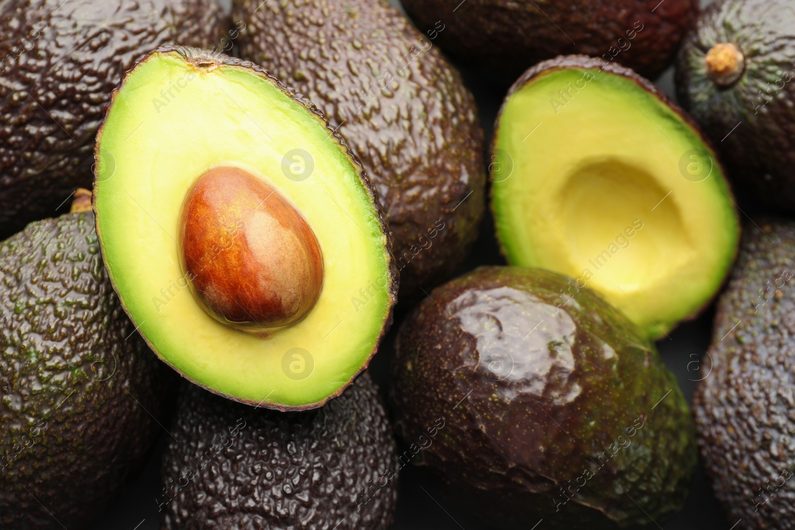 Photo of Many whole and cut ripe avocados as background, closeup