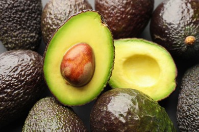 Photo of Many whole and cut ripe avocados as background, closeup