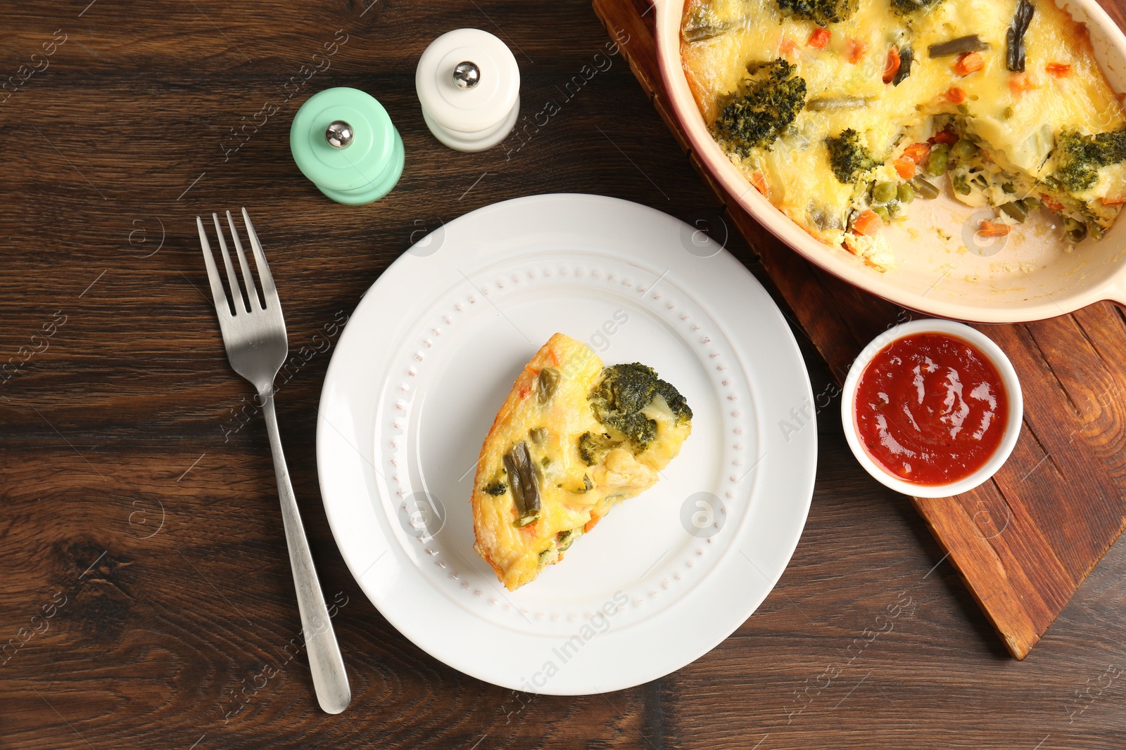 Photo of Tasty vegetable casserole served with sauce and spices on wooden table, flat lay